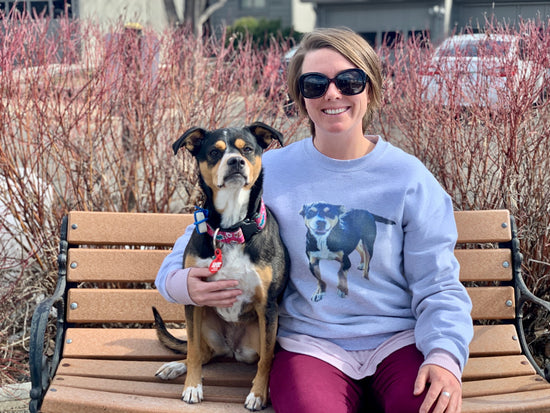 Woman wearing a custom My Pets Face sweatshirt with her tricolor dog sitting next to her